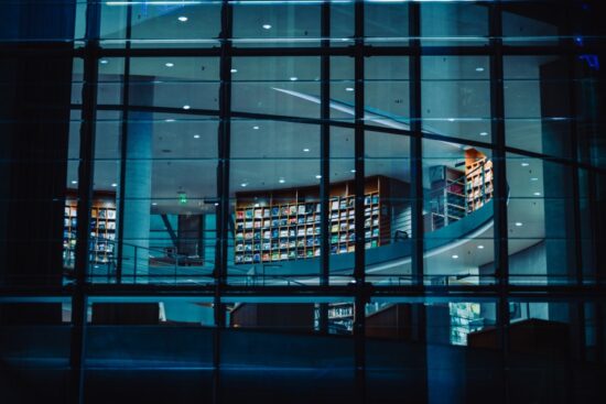 Moody, dark photograph of modern library through a window. Blue tones. Depicting CIAT CPD register due to architectural beauty.